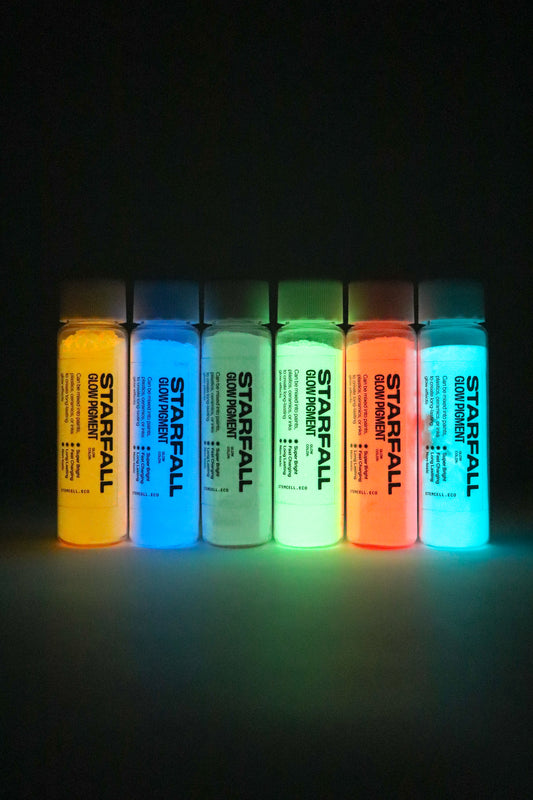 Set of six bottles of Starfall glow paint glowing in a dark setting