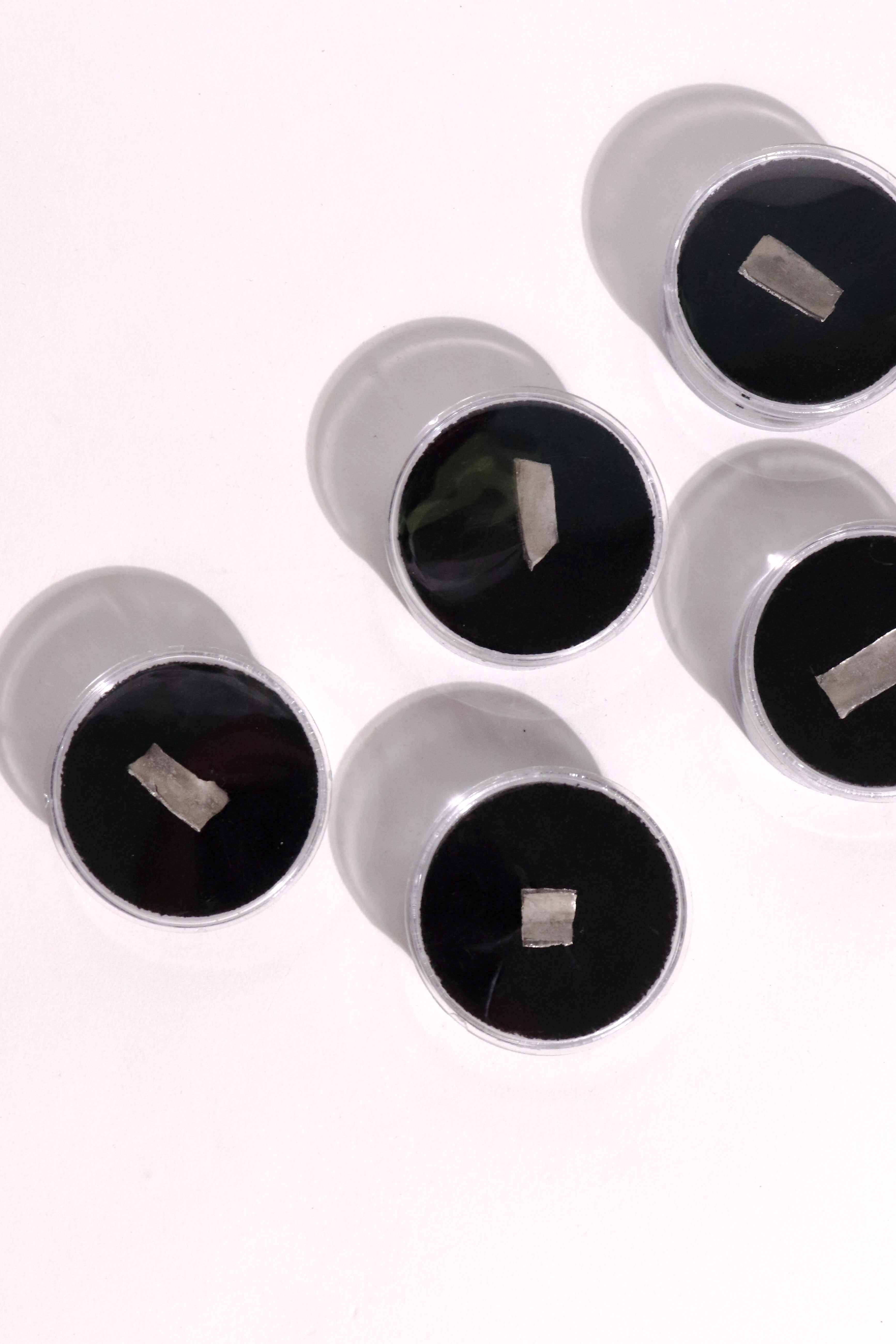Five silver-toned metal ear plugs with black velvet or faux-leather inserts, arranged on a plain white background.