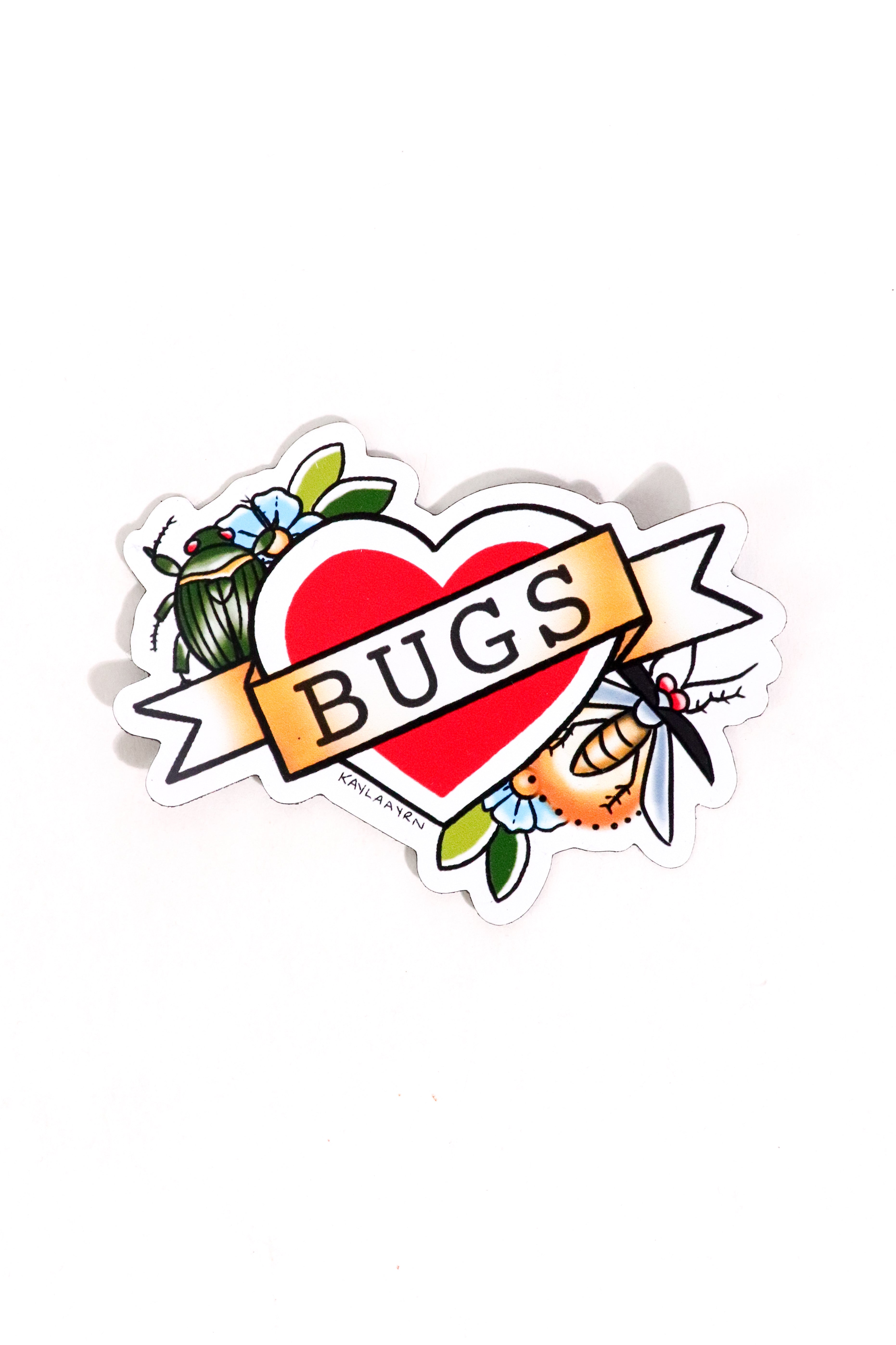 A die-cut sticker featuring a red heart with a banner reading 'BUGS' across it, surrounded by illustrated insects and small blue flowers, shown on a plain white background.